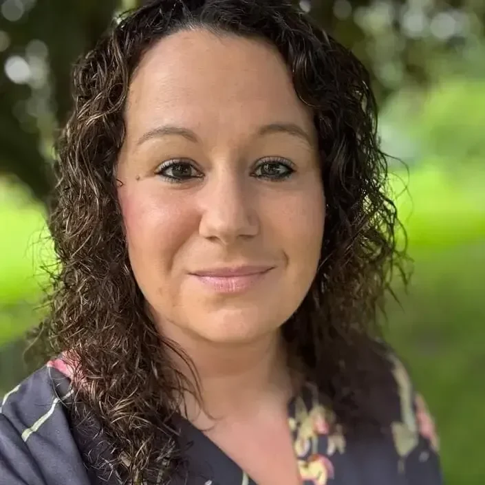 Mid-York CSR with brown eyes, curly brown hair, with a frank smile, with a pastoral background.