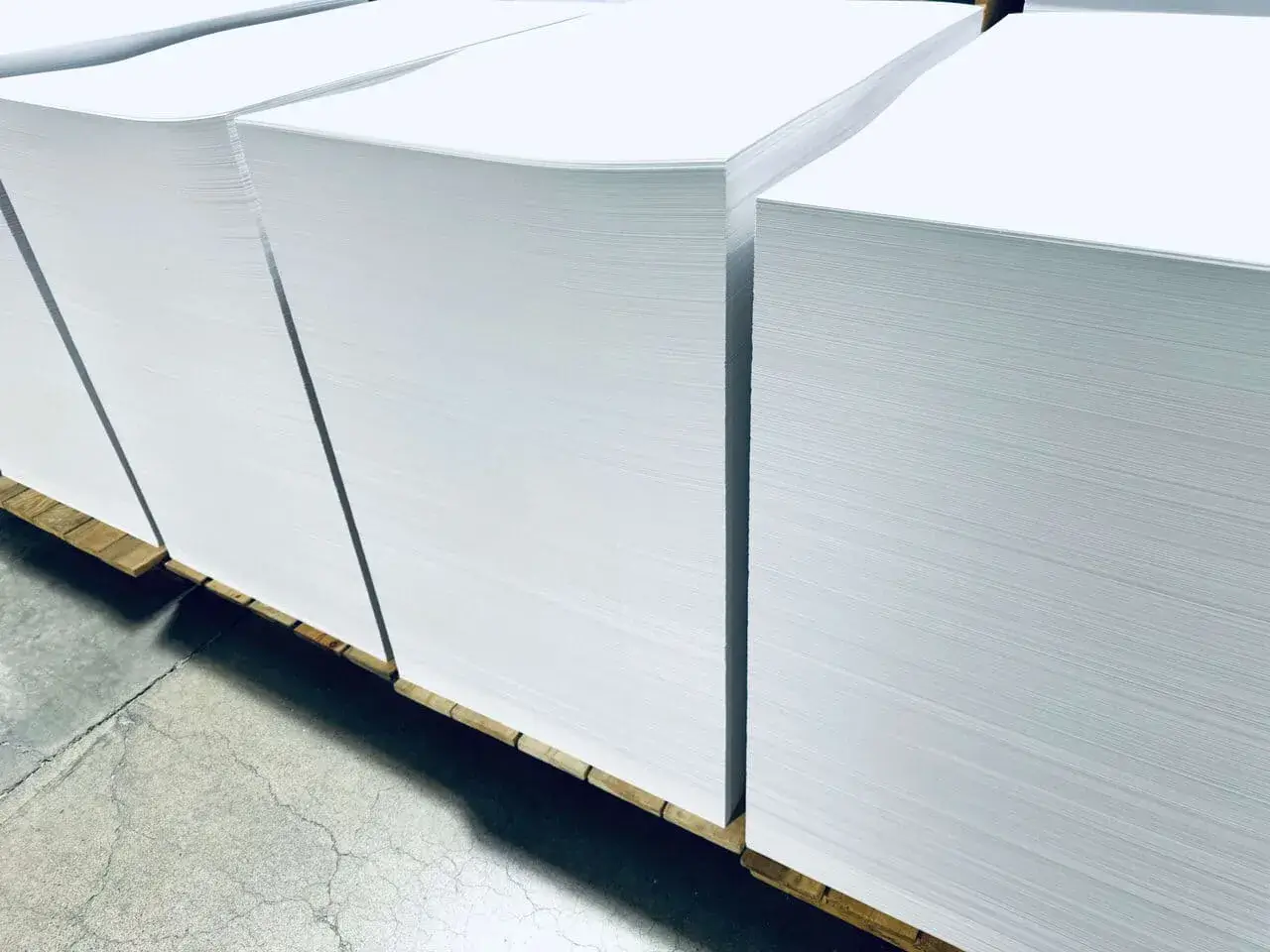 Sheeted stock on skids staged for the press, on a concrete floor